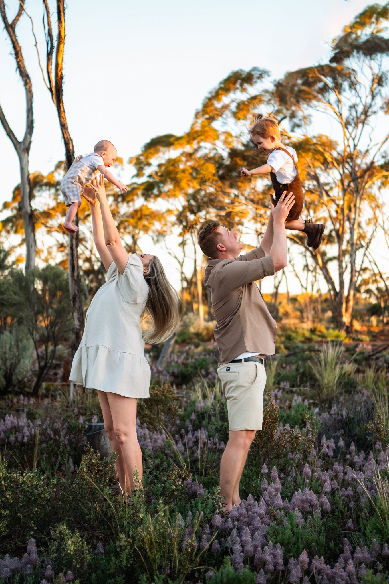 Children stroll along a rustic path at sunset during a golden hour outdoor family photo session.