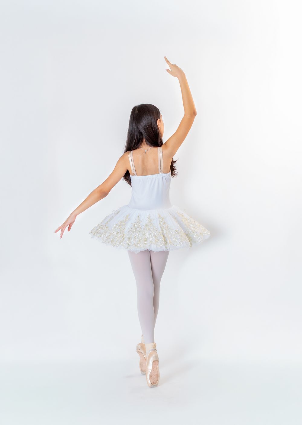 Ballet dancer in white tutu and pointe shoes performs graceful poses against light background in triptych composition.