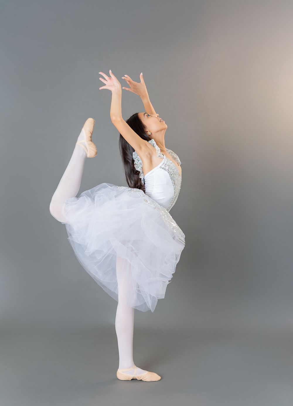 A ballet dancer in white performs a graceful high kick sequence across four progressive movement shots.