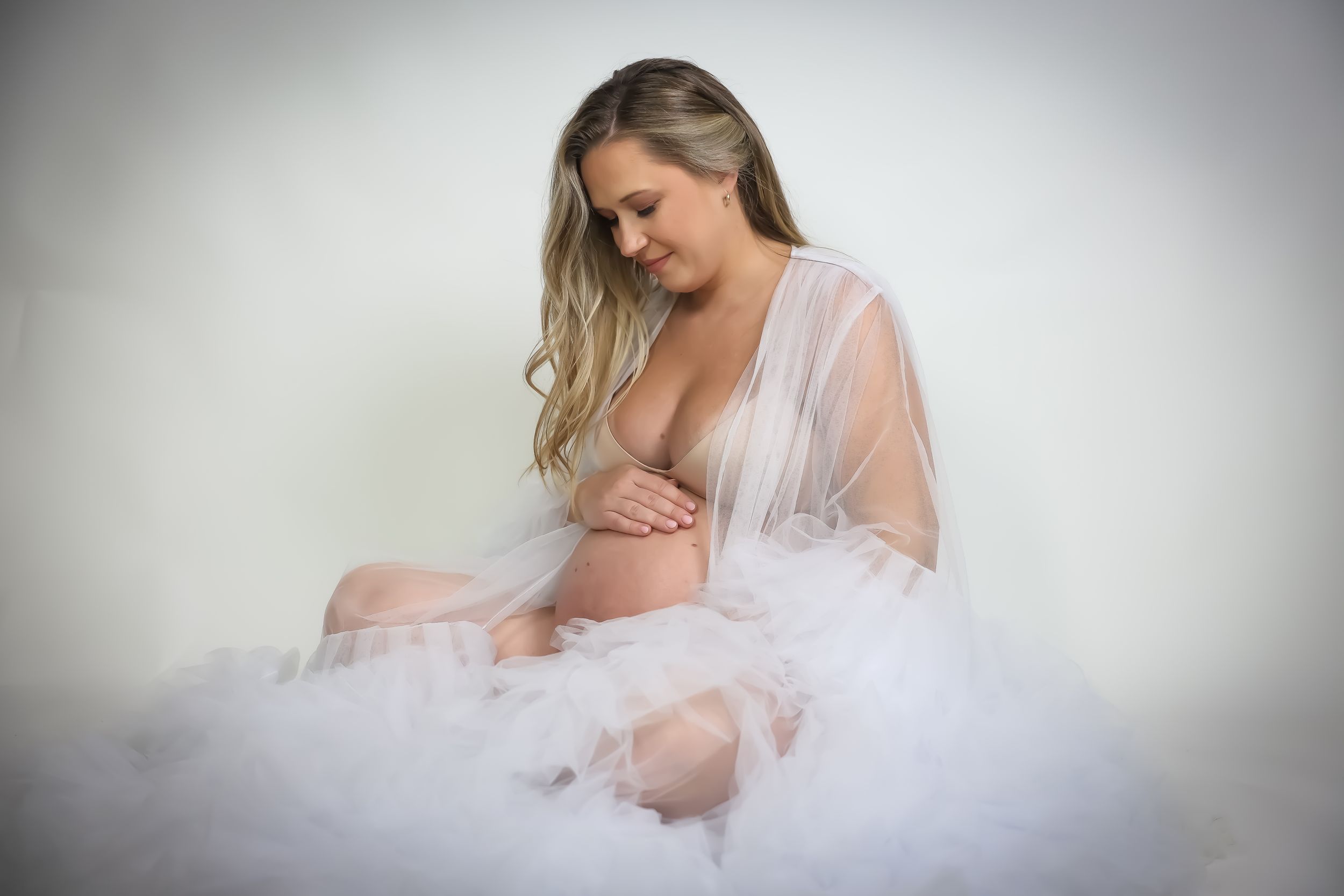 Dreamy maternity photos with soft lighting and flowing white fabric.