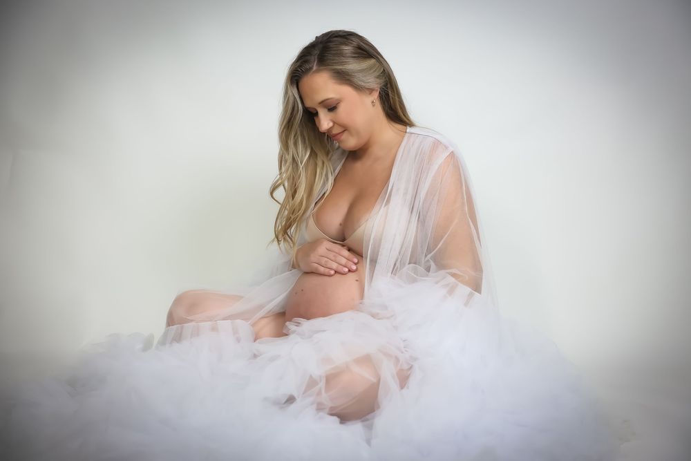 Dreamy maternity photos with soft lighting and flowing white fabric.