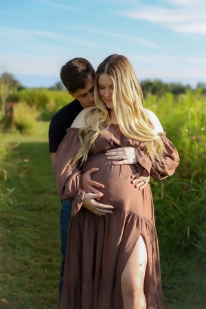 An intimate maternity portrait in a grassy field on a sunny day.