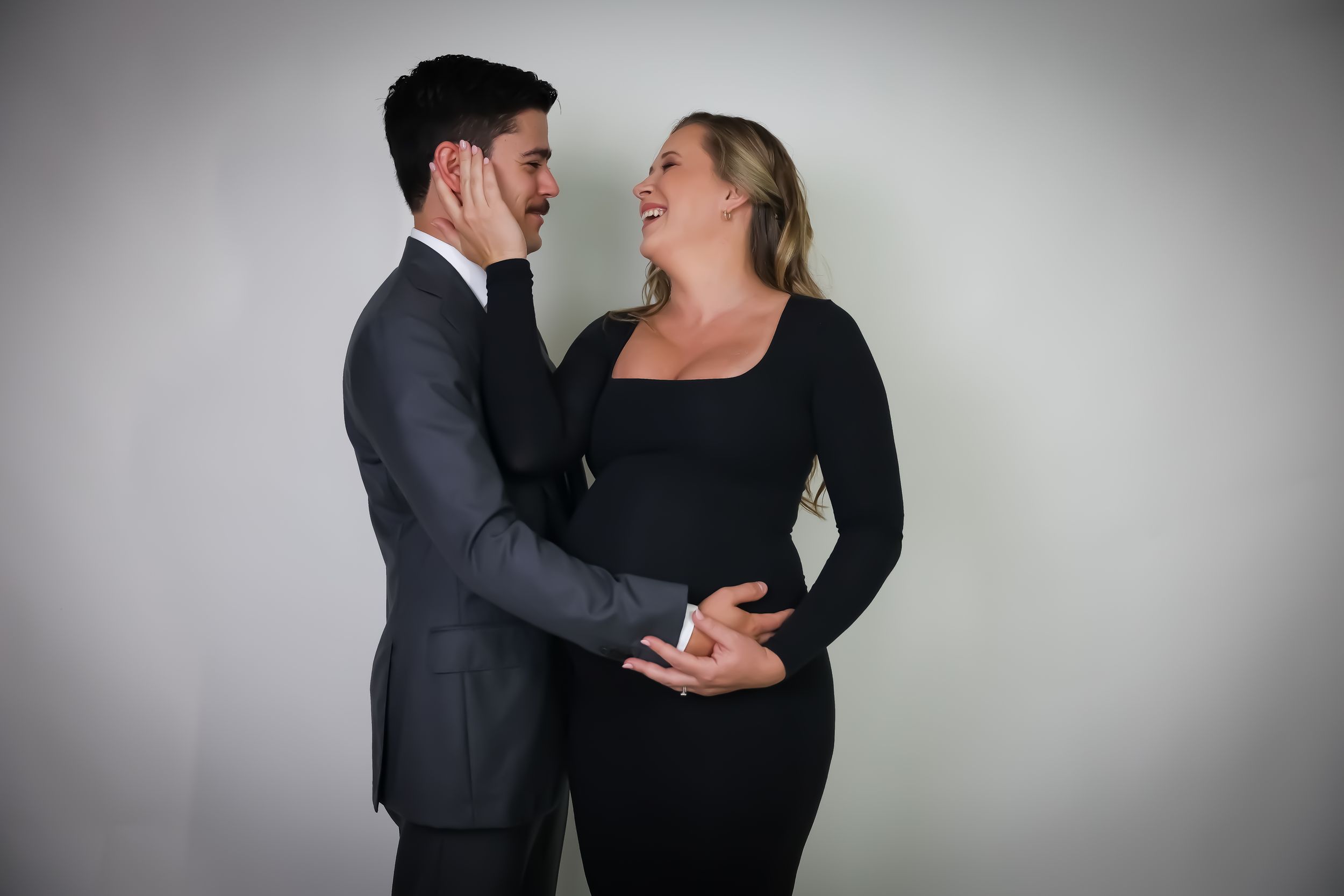 Romantic couple photoshoot with dramatic lighting against a grey studio backdrop.
