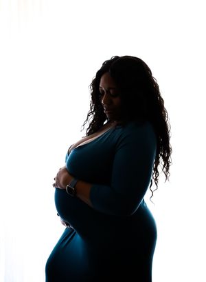 Dramatic silhouette maternity portrait highlighting pregnancy curves against white background.
