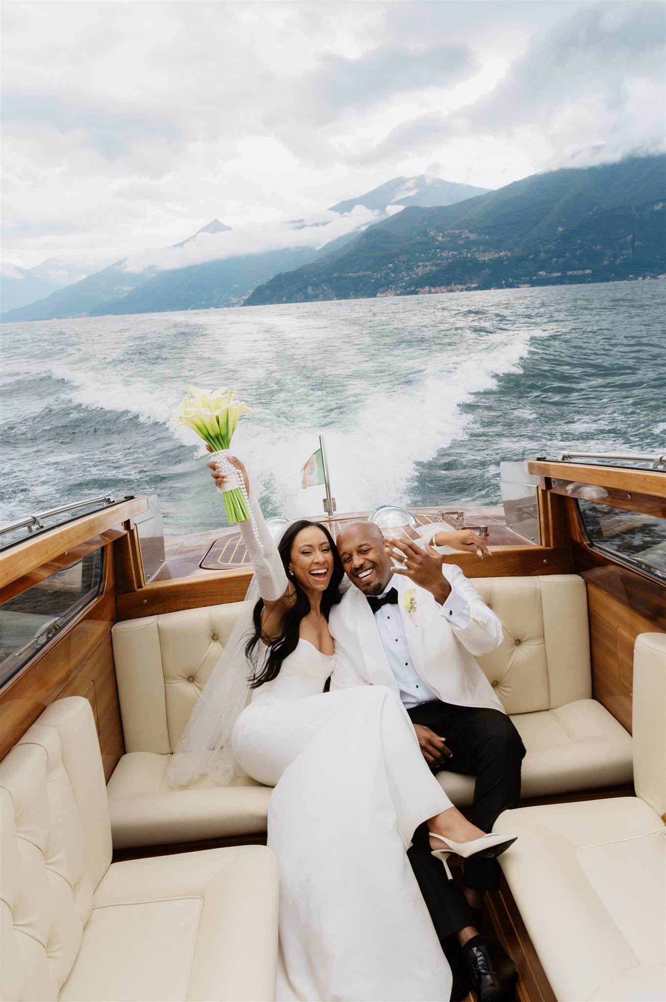 A couple celebrates on a luxury boat with mountains and lake views in the background.
