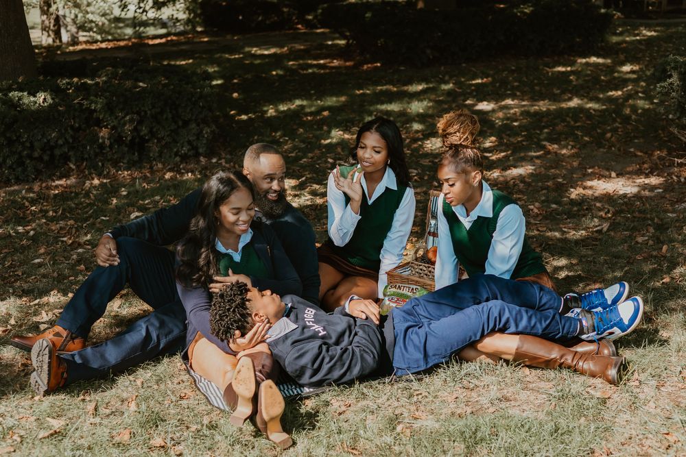 A group of people lying down on grass in a row during an outdoor photo session.