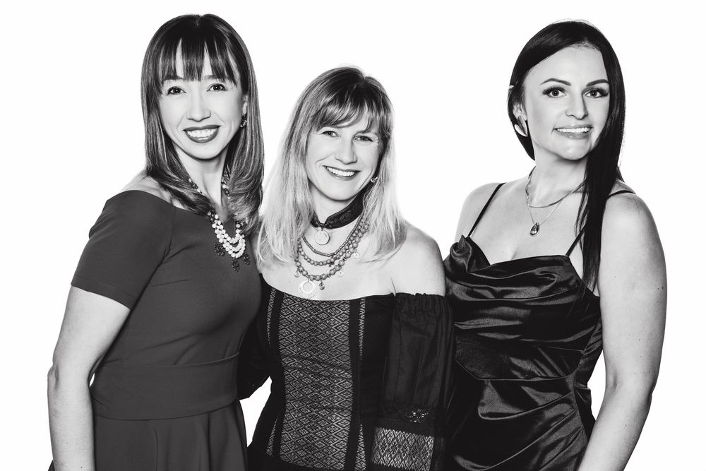 Professional black and white portrait of business team members standing together in formal attire.