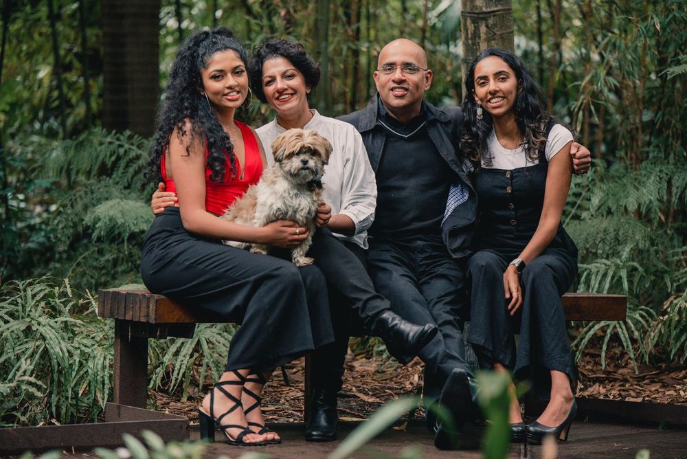 A family poses together for outdoor portraits in a lush green garden setting.