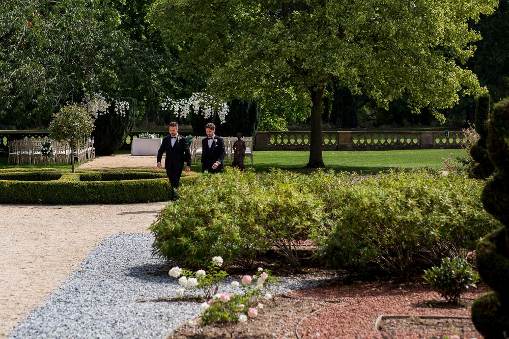A formal garden pathway lined with trimmed hedges and flowering plants.