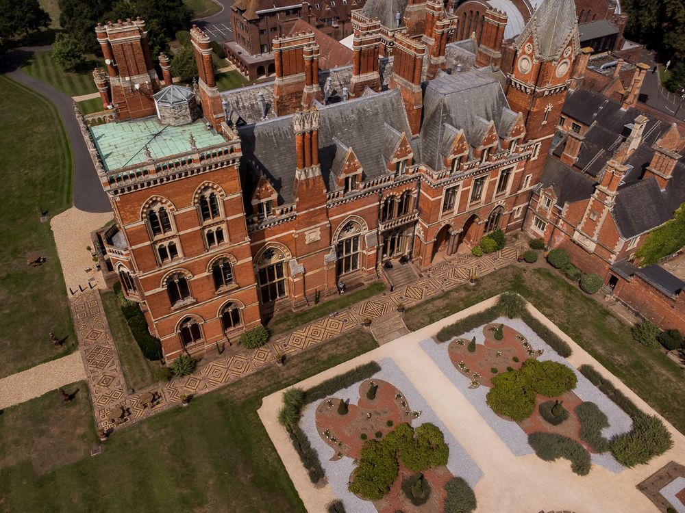Aerial view of a grand Victorian Gothic mansion with red brick facade and ornate architectural details.