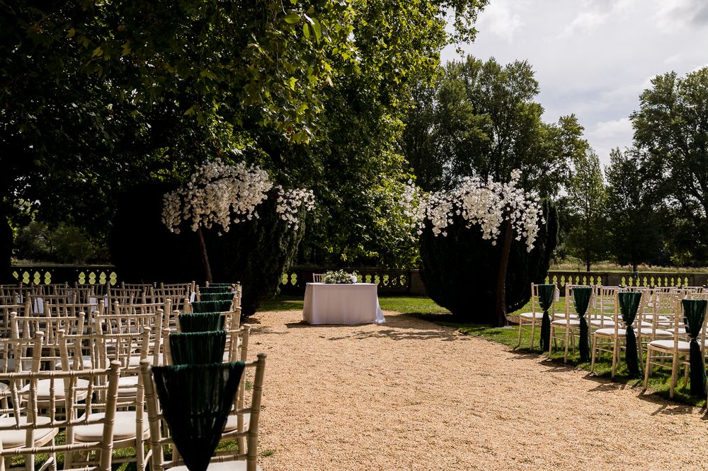 Garden wedding venue with rows of chairs and hanging decorations along a gravel path.