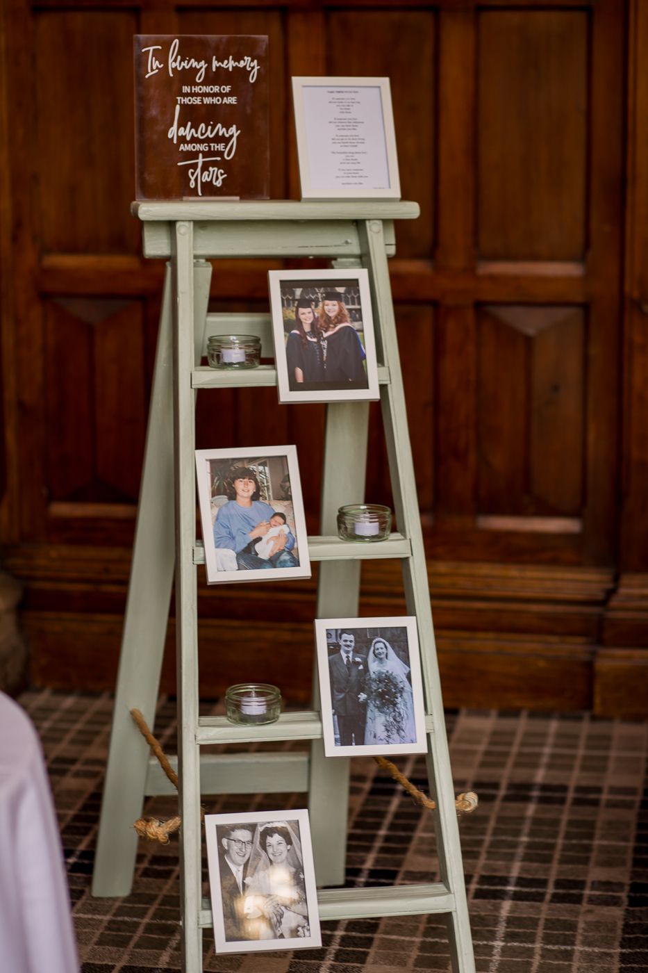 A mint green ladder shelf decorated with photos and candles for a wedding display.