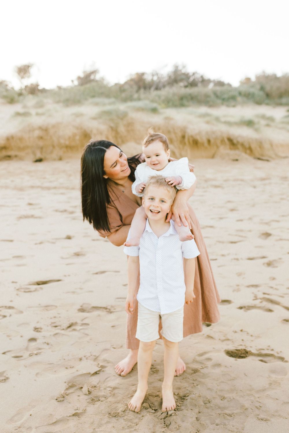 A family enjoying time together on a sandy beach during a warm sunny day.