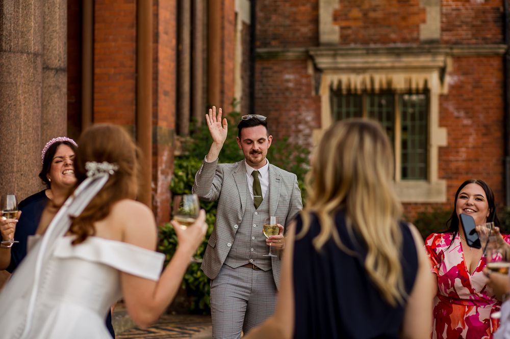 Wedding guests socialize and celebrate outside historic brick venue with columns.