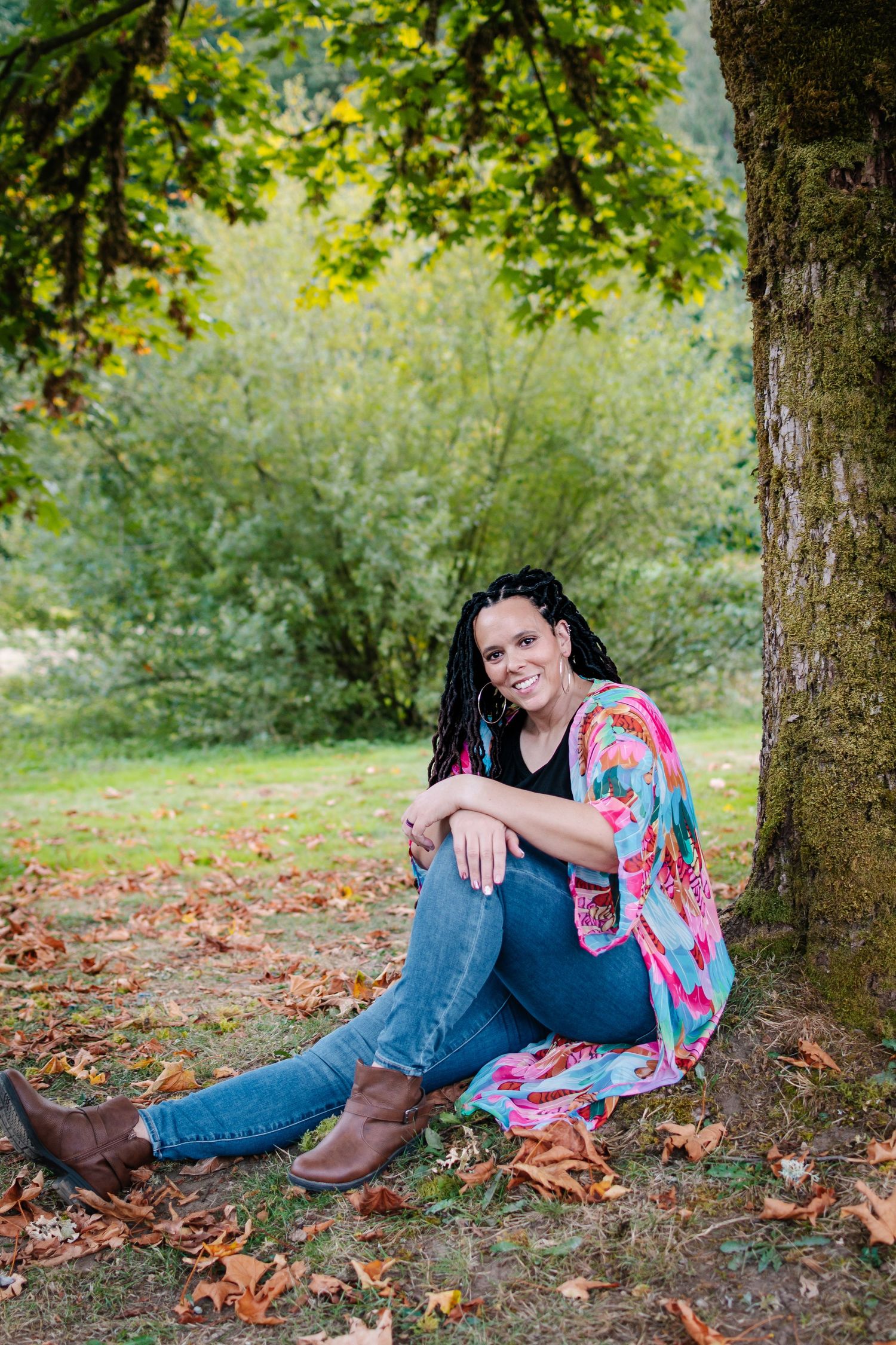 Woman sitting under trees during fall portrait session at Flaming Geyser State Park near Tacoma, WA.