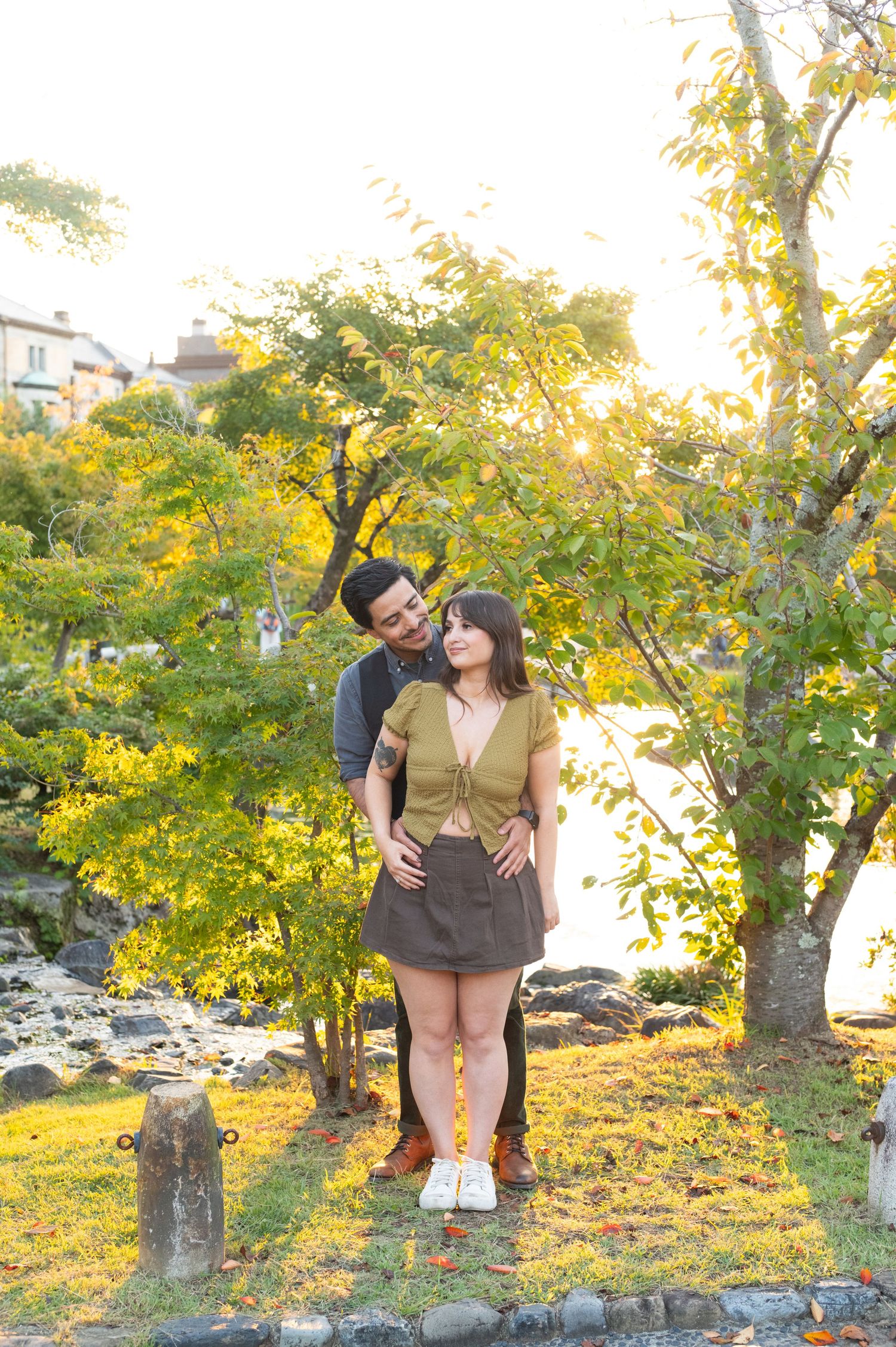 Couple embracing among golden autumn trees in a serene park setting.
