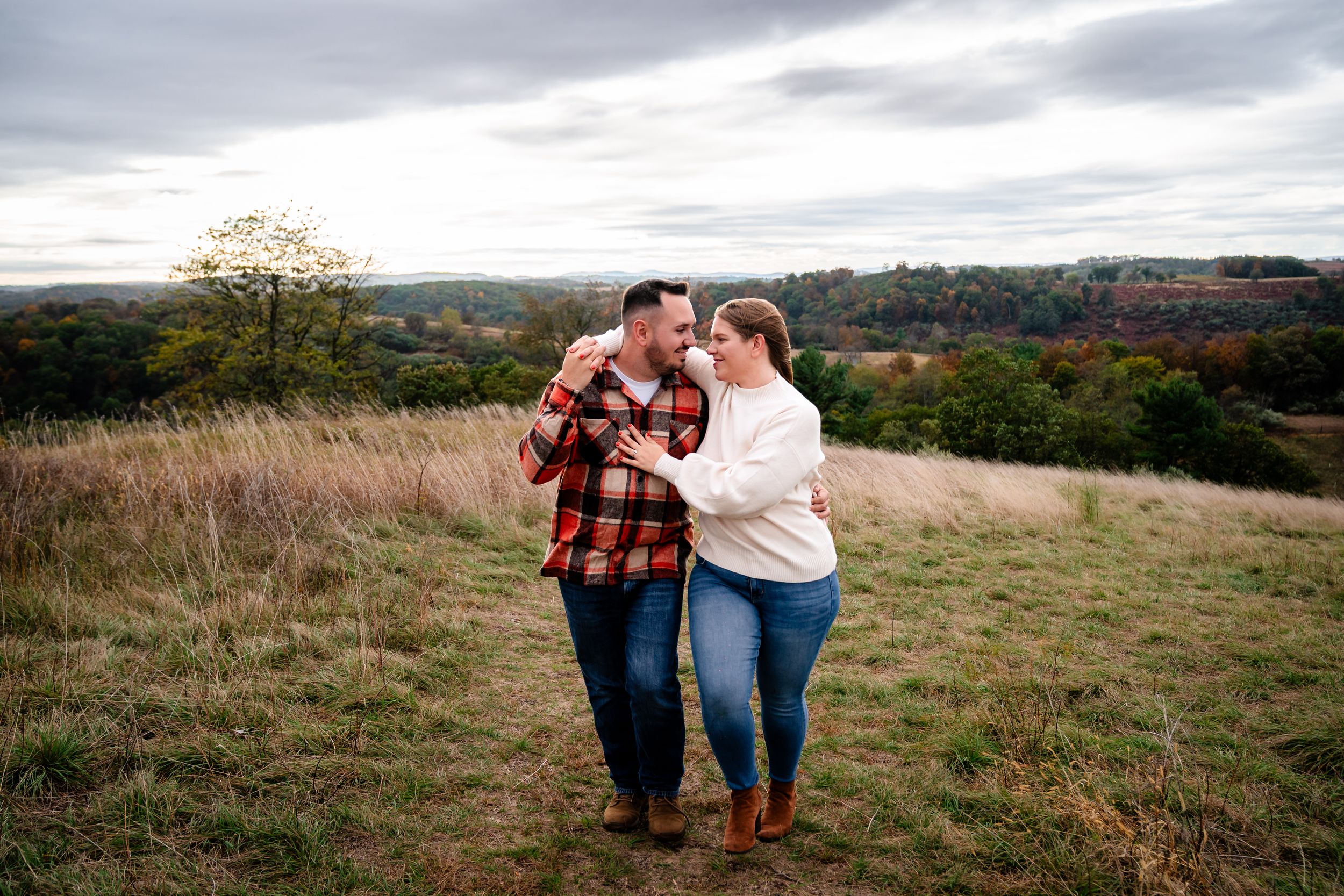Two people enjoying a tender moment together in a hilltop meadow during fall.