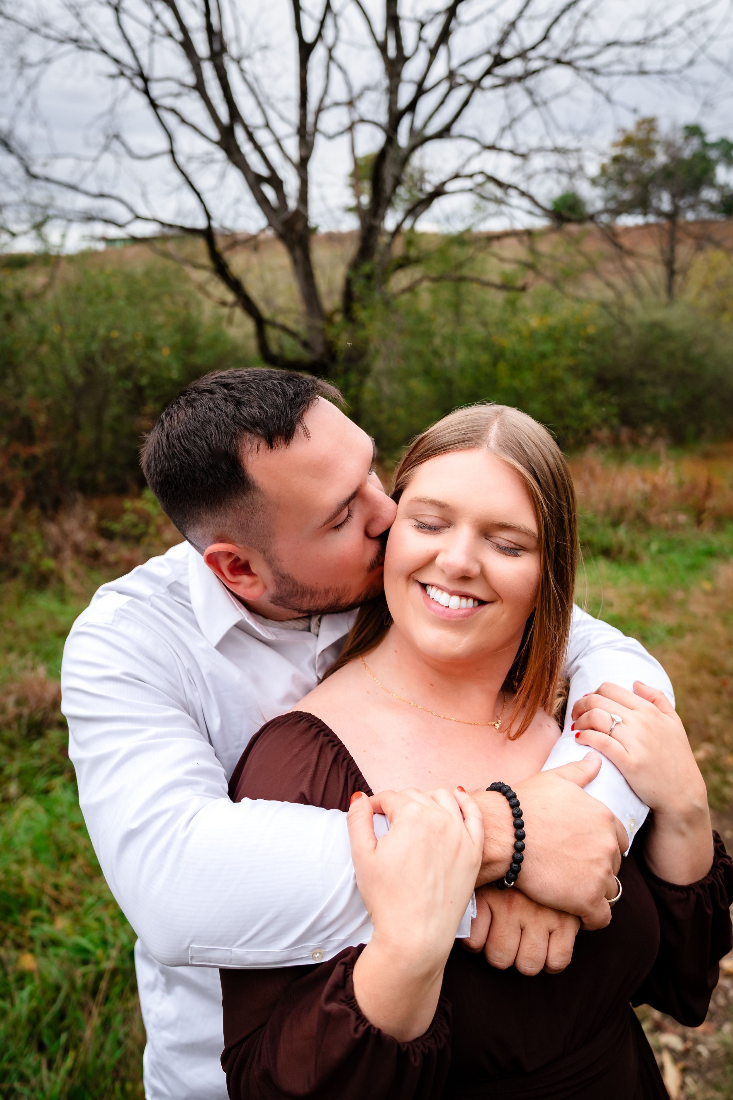 A romantic outdoor autumn photoshoot showing an intimate embrace in a natural setting.