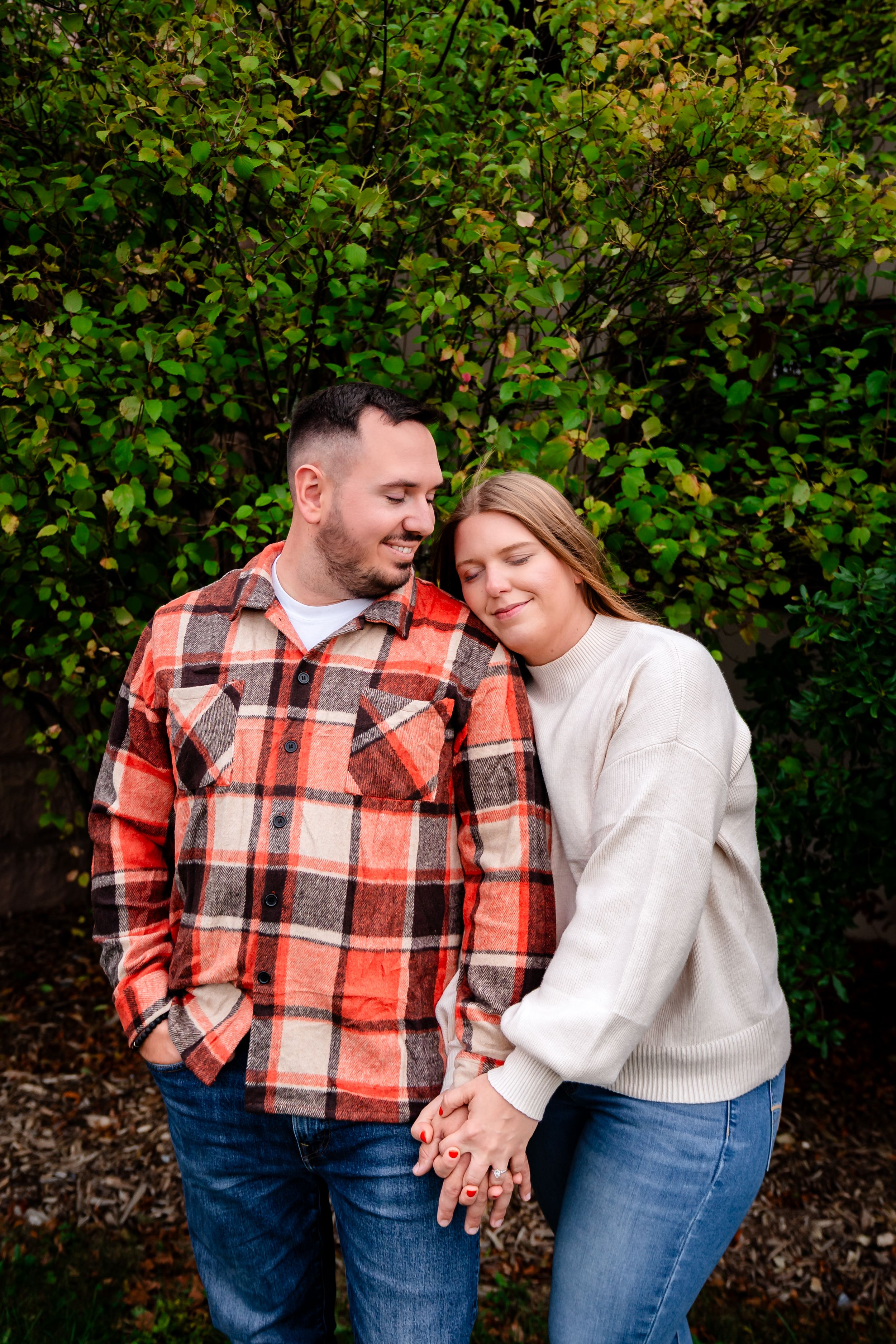 Couple sharing tender moment against autumn foliage background.
