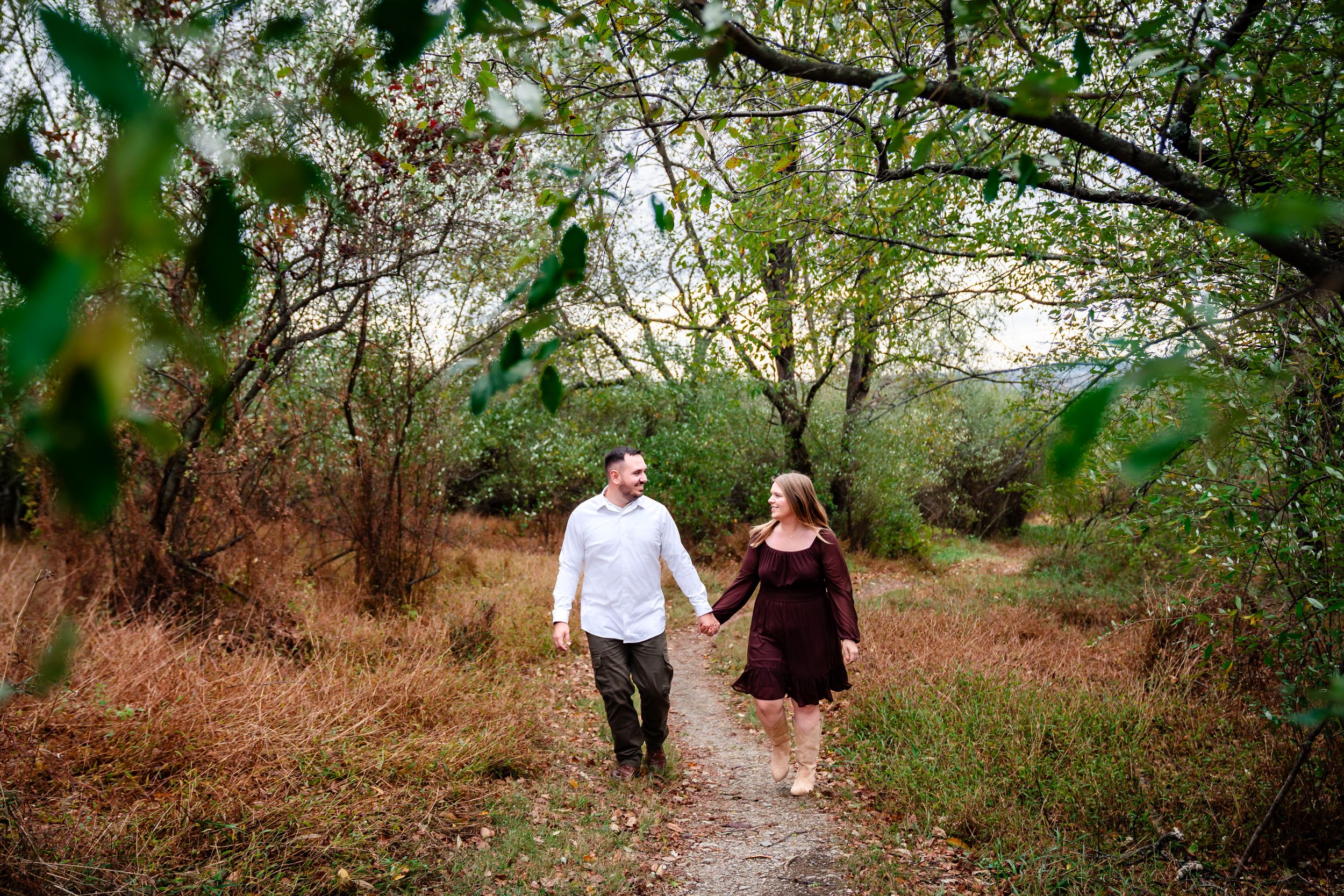 Romantic woodland engagement session with natural greenery backdrop.