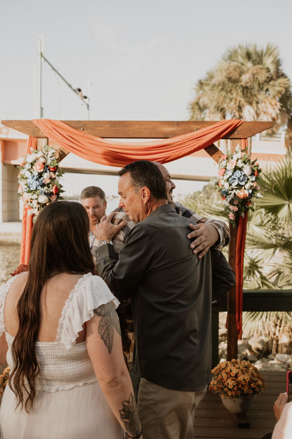 A romantic wedding ceremony moment captured in a series of photos showing a couple embracing under a coral-colored canopy.