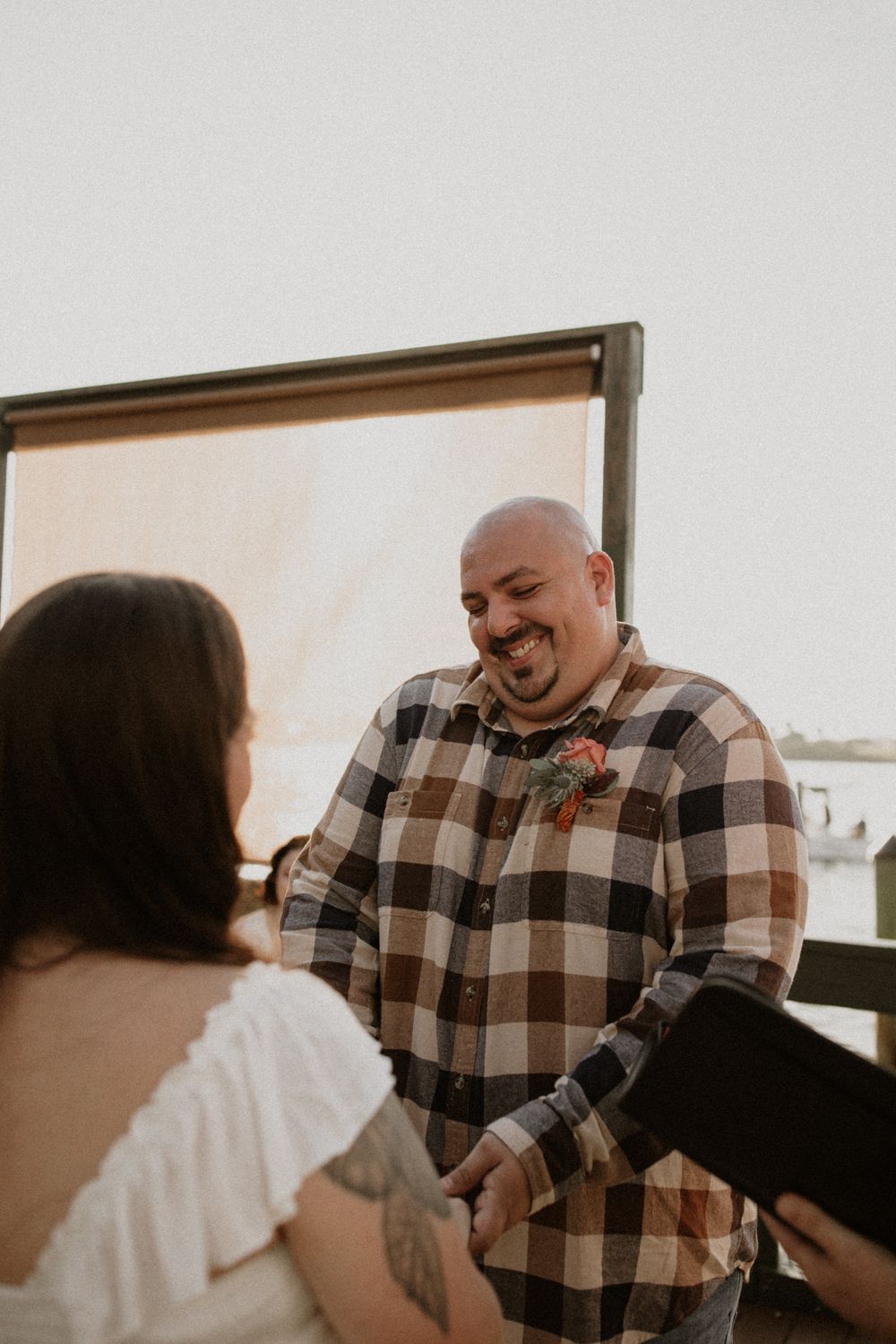 A couple shares an intimate moment during a wedding ceremony in front of a white backdrop.