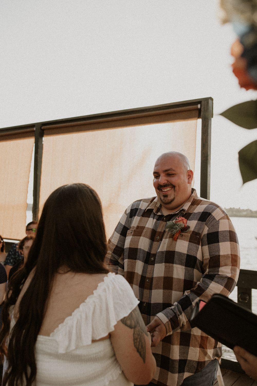 A joyful moment during a waterfront wedding ceremony with a couple sharing laughter under natural lighting.
