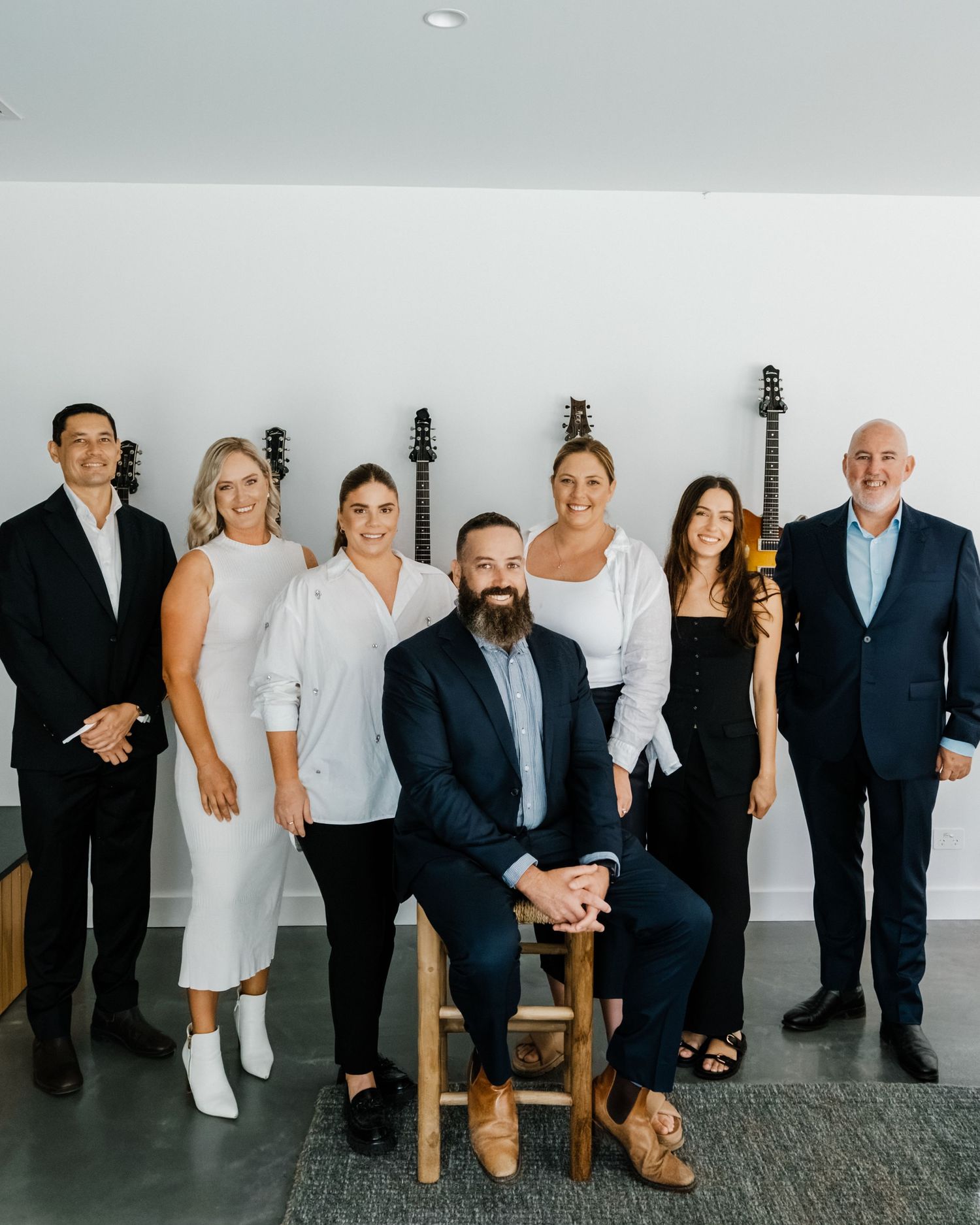A creative wedding party photo showing only the legs and feet of people lined up against a gray wall.