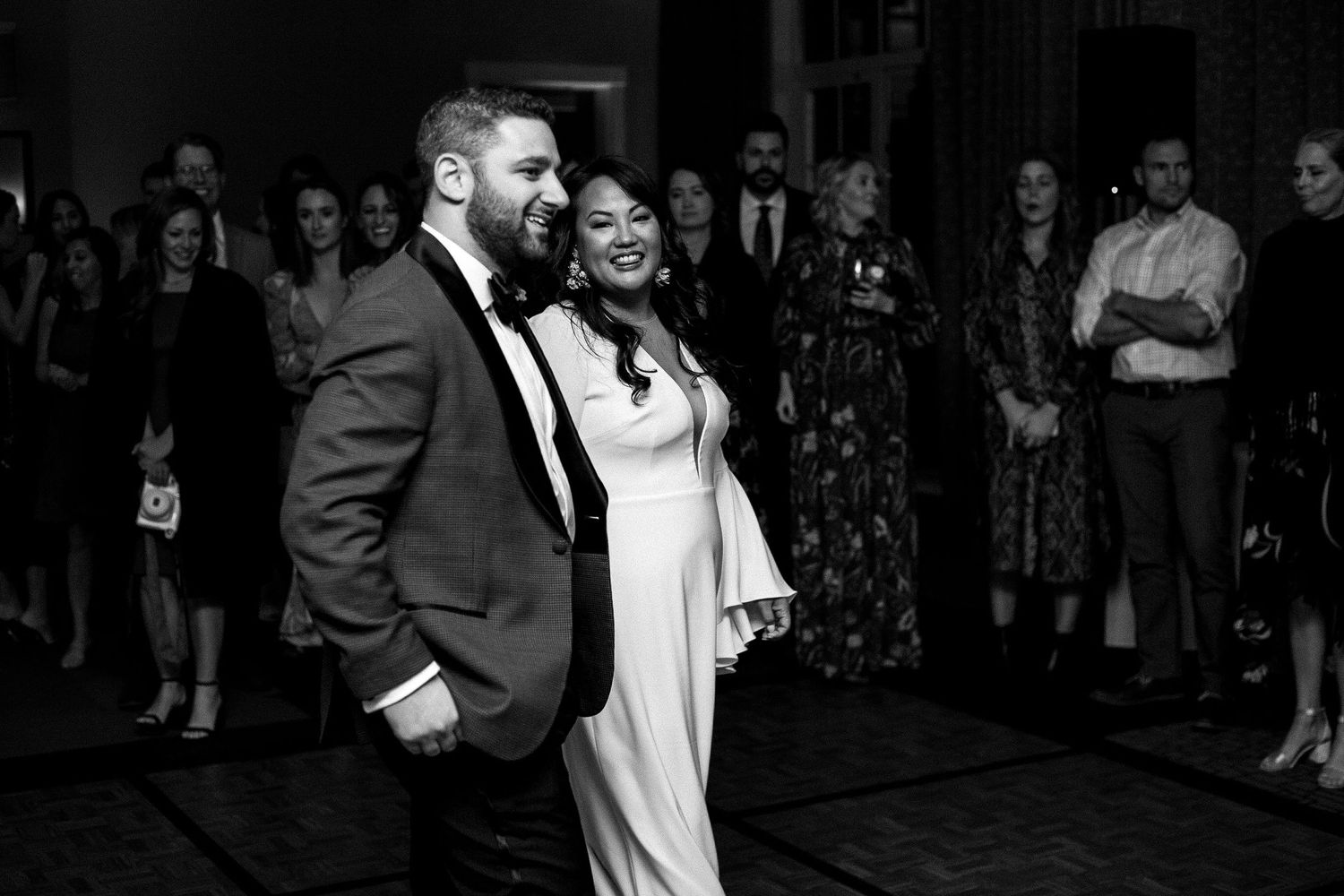 Wedding guests dance and celebrate together at a lively reception with dark lighting and festive atmosphere.