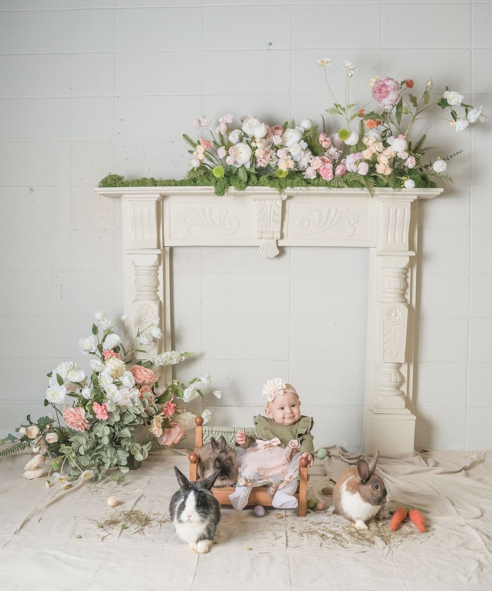 Vintage white fireplace mantel decorated with pink and white flowers, surrounded by rabbits and Easter decor.