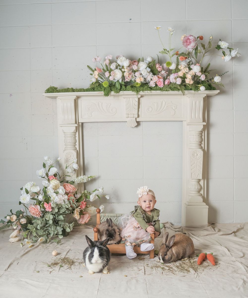 White vintage headboard decorated with delicate pink and white floral arrangements against a light gray backdrop.