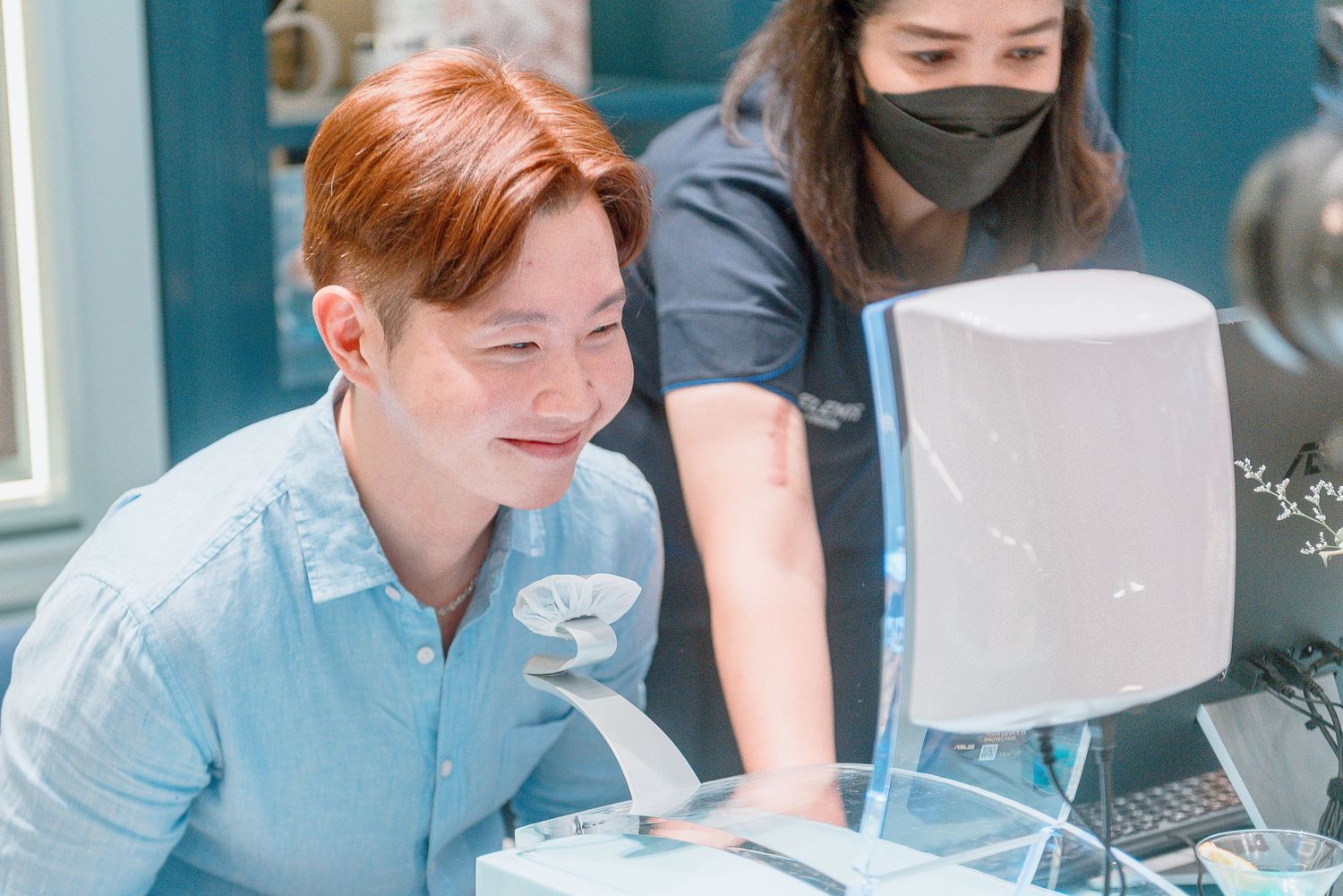 Students working together at computers in a modern office space with blue walls and natural lighting.