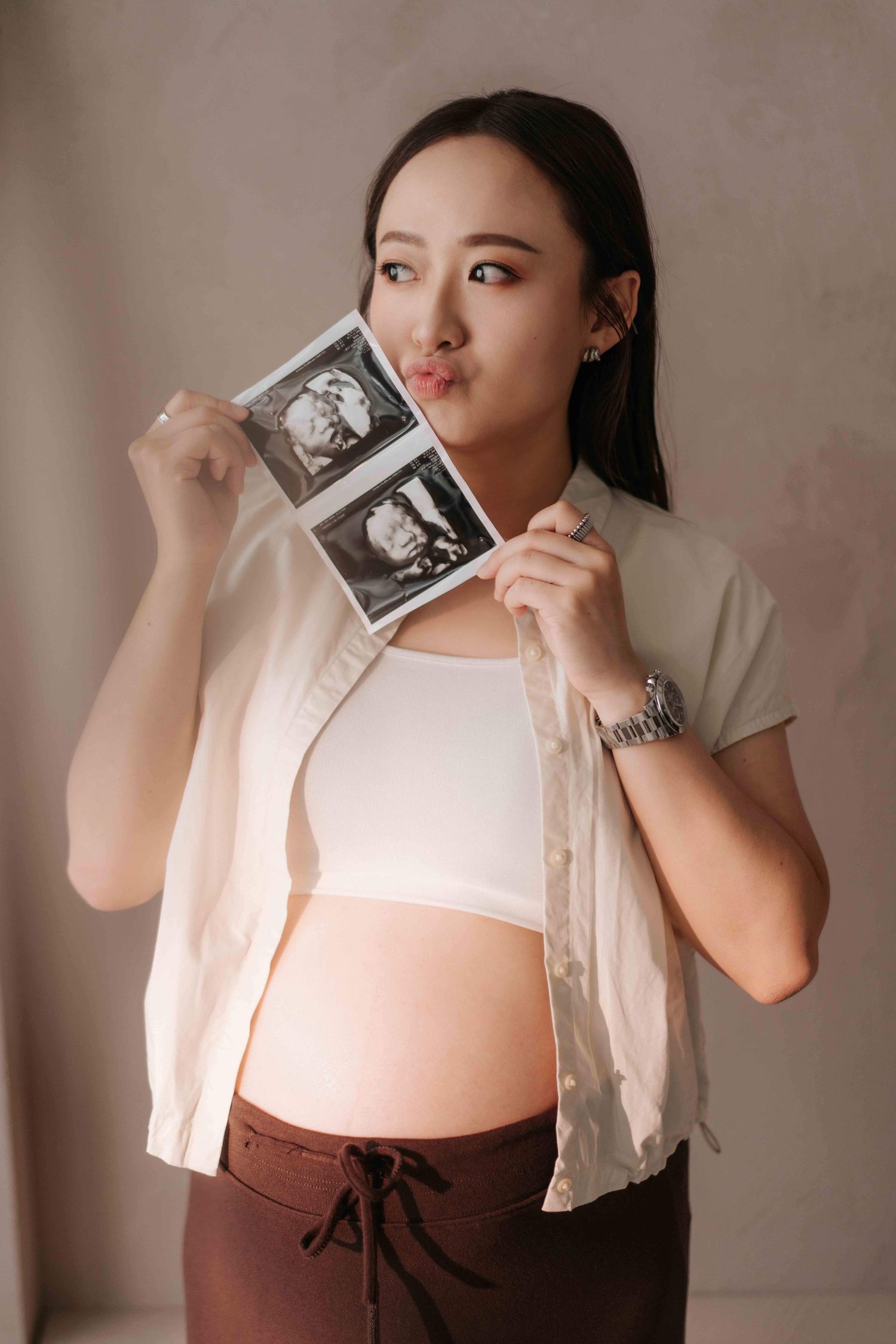 Maternity photo series featuring a white blouse and burgundy dress with ultrasound photo poses孕婦寫真係列，模特兒身穿白色襯衫和酒紅色連身裙，擺出超音波照片的姿勢。