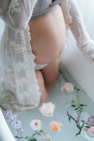 Delicate lace maternity dress detail with soft pink and purple flowers arranged on a light background.精緻的蕾絲孕婦裝，飾以柔和的粉紅色和紫色花朵，點綴在淺色背景上。