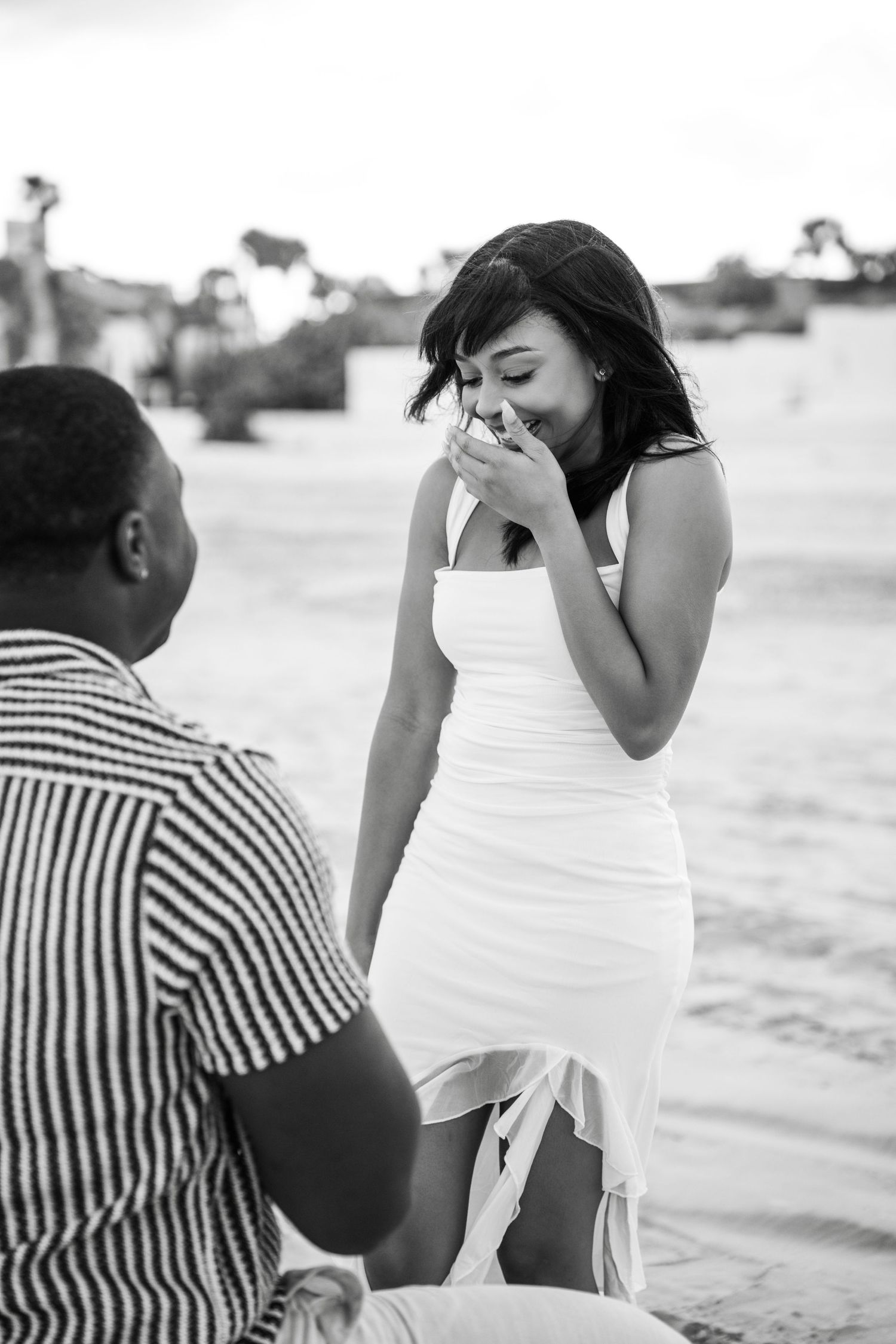 A surprise proposal moment captured on coastal rocks in black and white photography in Daytona Beach Florida