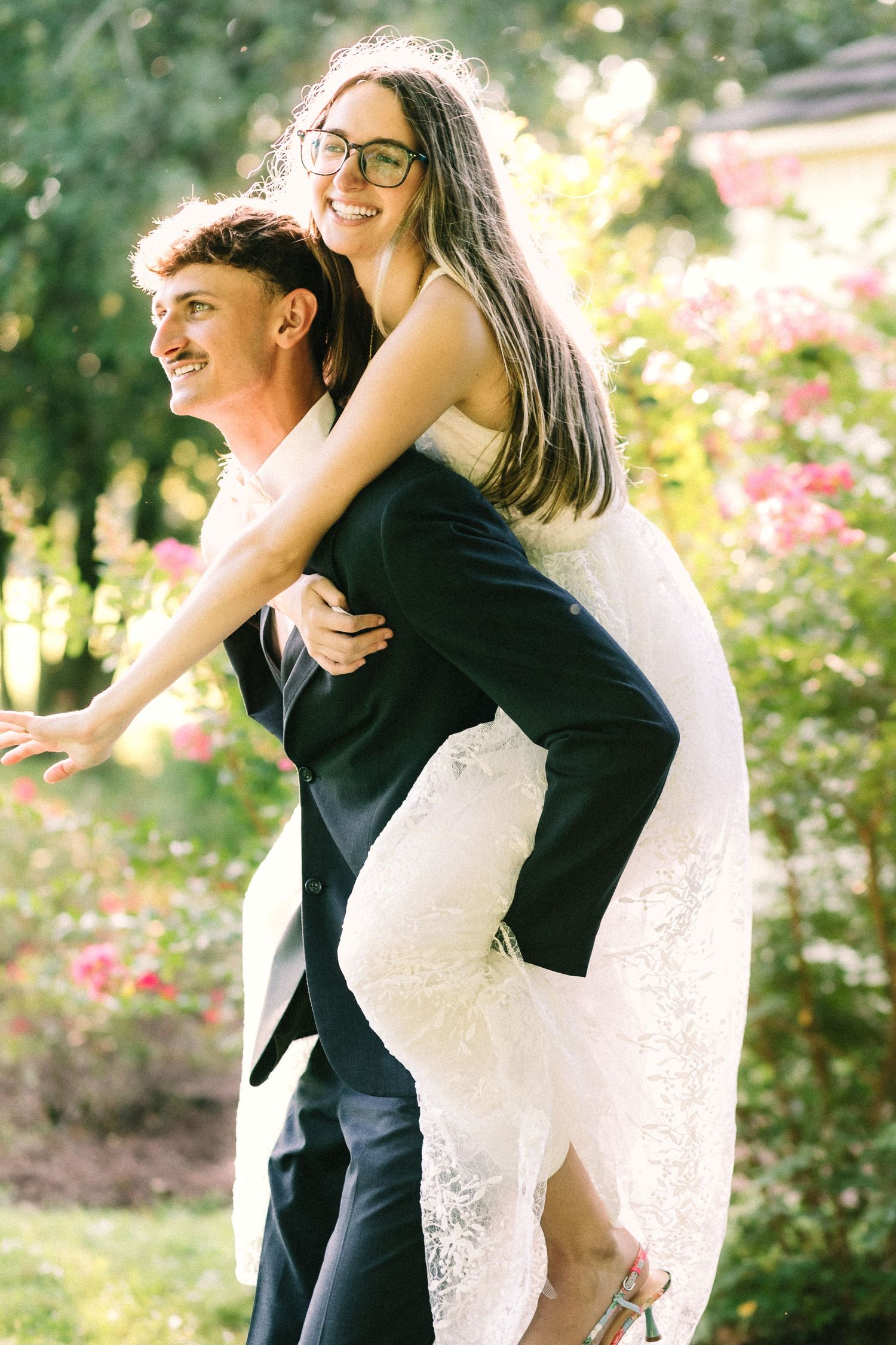 A couple shares joyful moments in a garden setting with blooming flowers and natural sunlight.