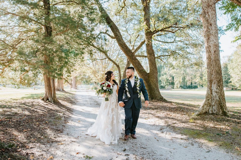 Wedding party walking along a tree-lined path in a natural outdoor setting during a sunny autumn day.