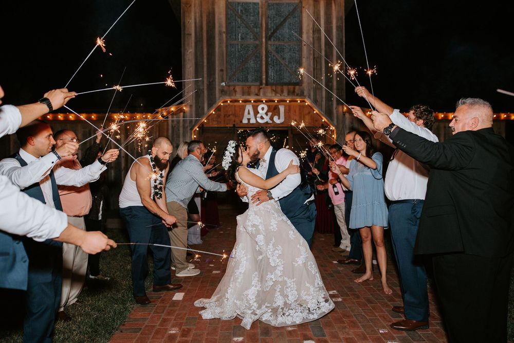 Wedding reception dance floor filled with guests celebrating under string lights at night.