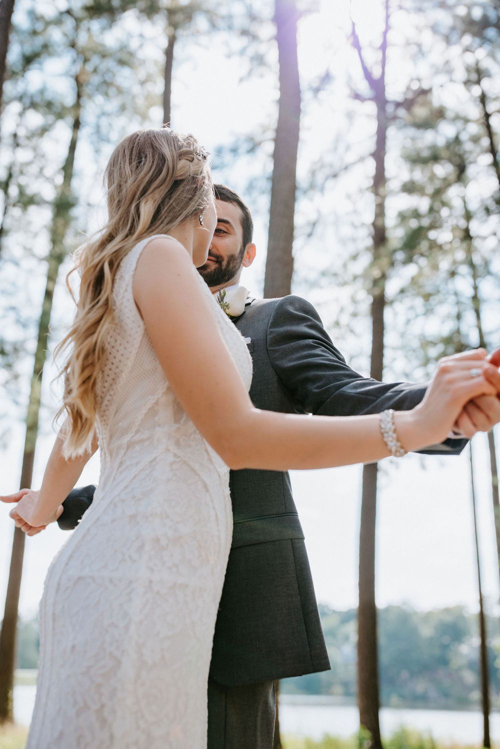 A sequence of three photos showing a couple in wedding attire dancing in a wooded area near a lake.
