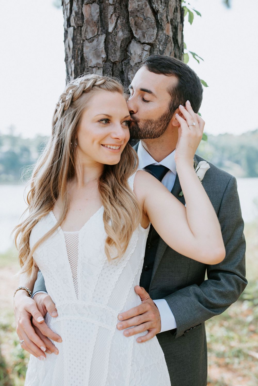 Romantic couple in wedding attire share intimate moments in a series of outdoor portraits against a natural backdrop.