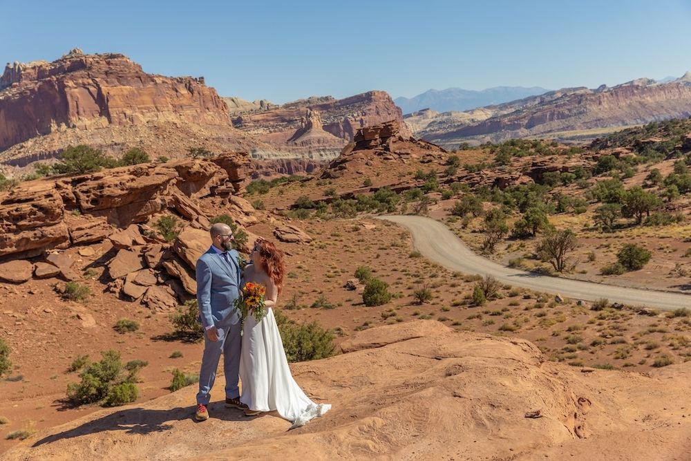 Wedding portraits captured against dramatic red rock formations in a desert landscape at sunset.