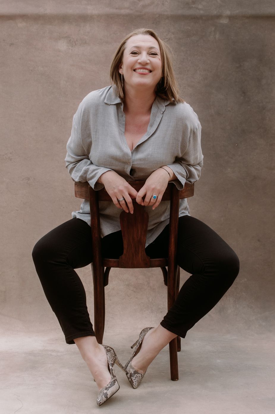 Four sequential photos show a person in gray top and black pants sitting casually on a wooden chair against neutral backdrop.