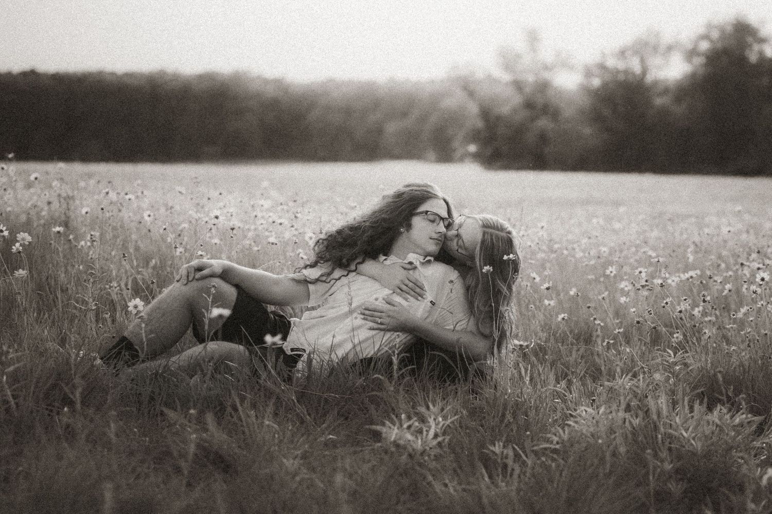Couple embracing romantically in a wildflower field in a vintage black and white photo.