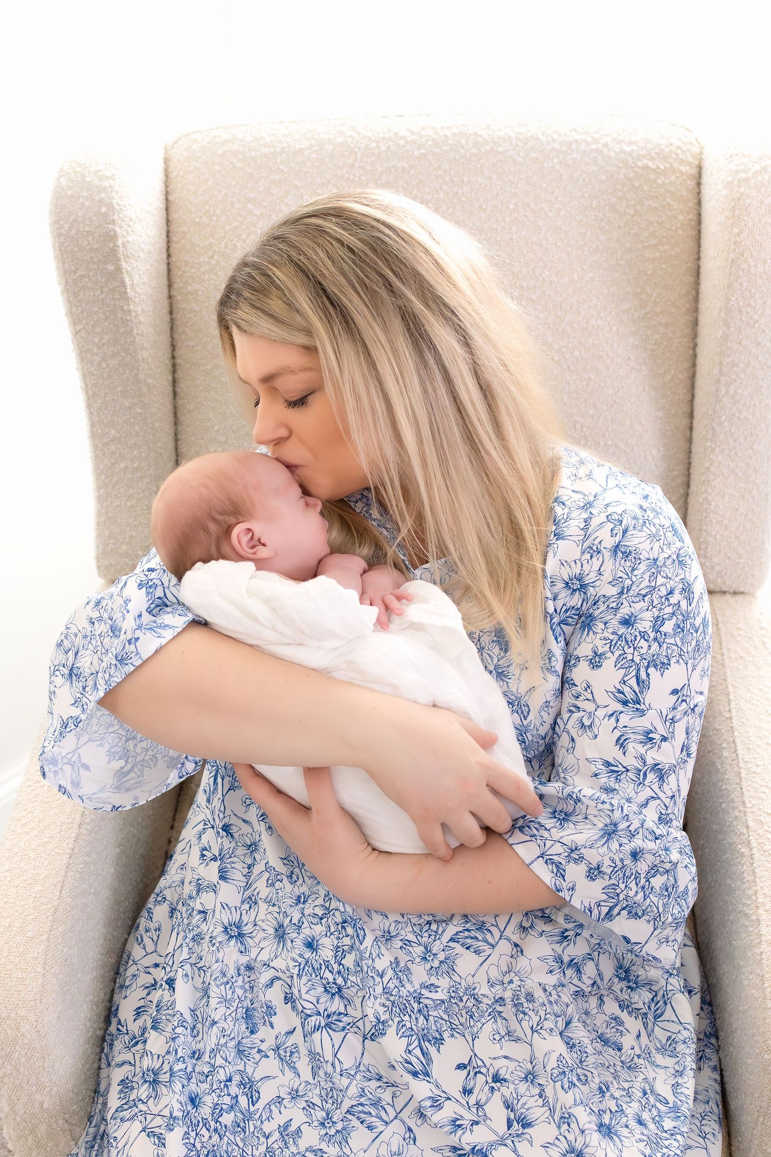 Mother holding her newborn baby near window light during North Georgia lifestyle newborn photography session.