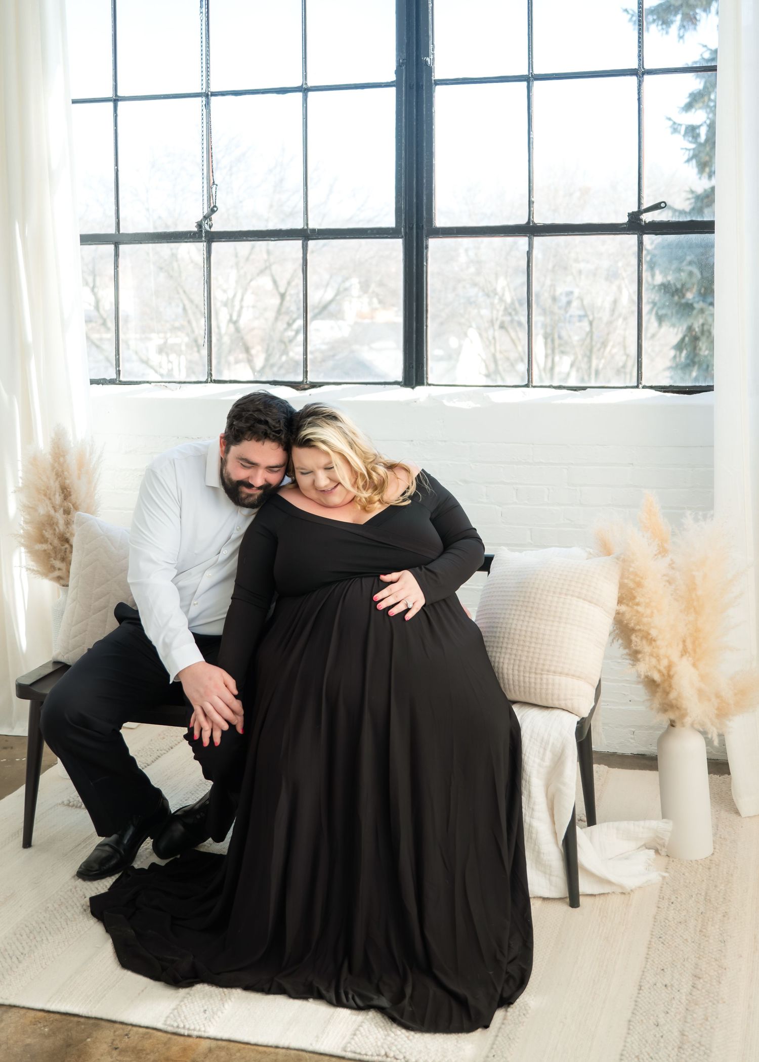 A series of four photos showing a couple in black attire posing together on a white sofa with pampas grass decor.