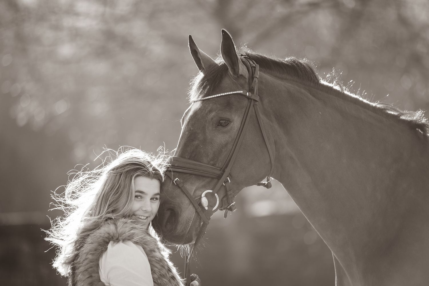 A majestic horse with flowing mane stands in profile against a soft, blurred background in black and white.