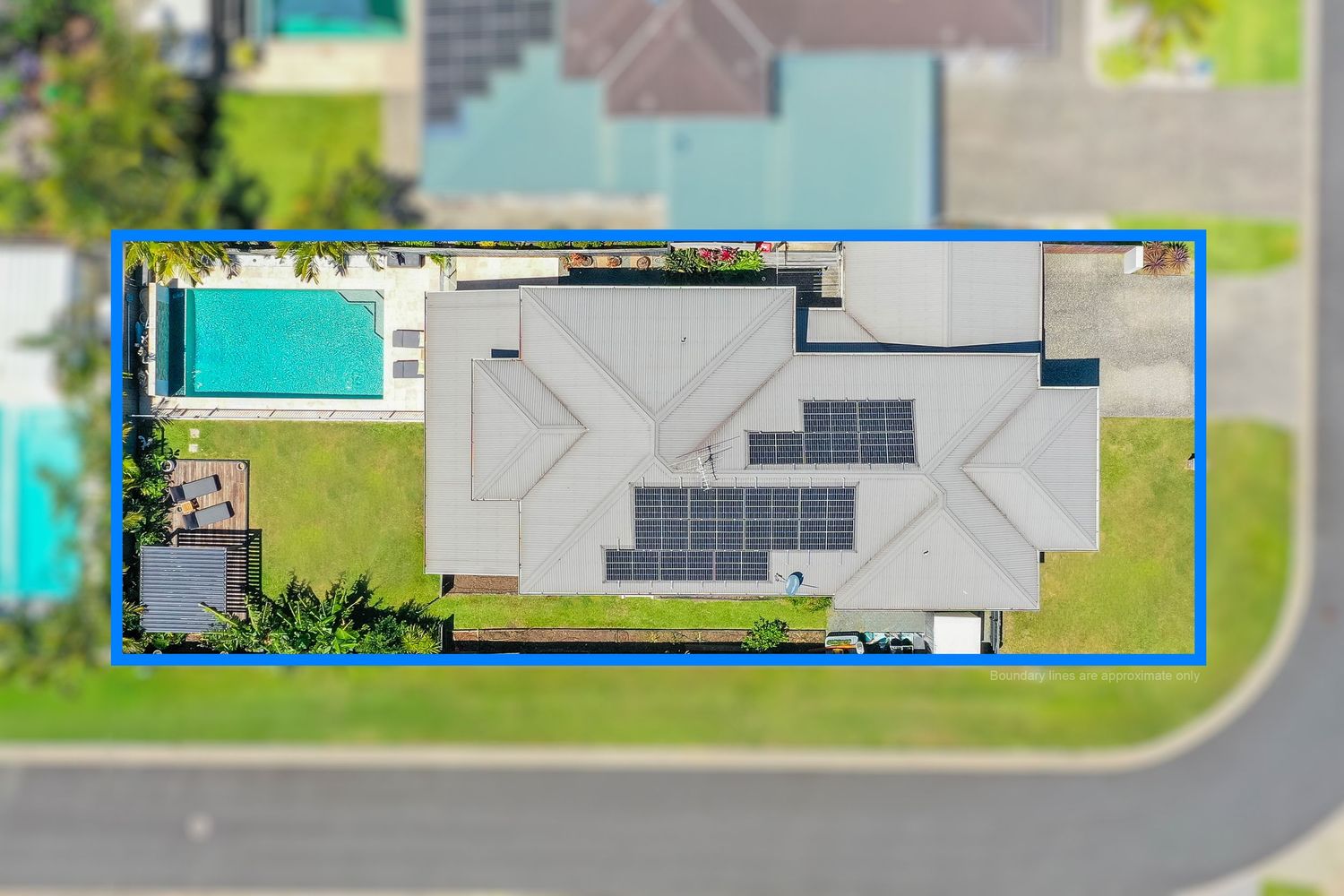 Aerial top-down view of a modern home with solar panels, pool, and blue boundary outline on a corner lot.