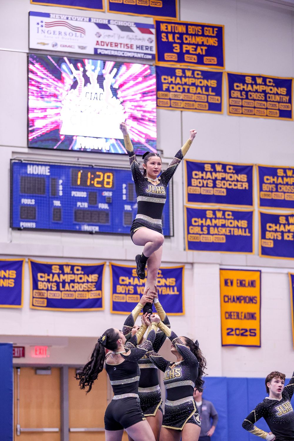 Cheerleaders perform a stunning stunt at an SWC championship gym, with one flyer raised high during a 2025 competition.