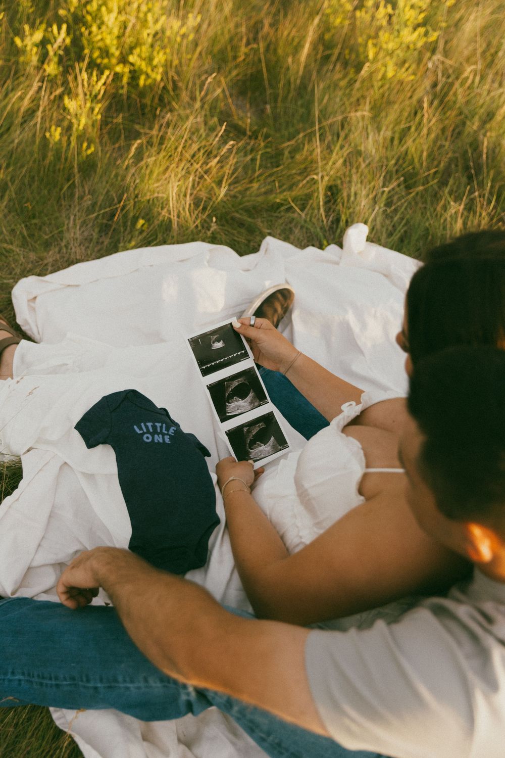 Someone lying down while holding an ultrasound photo against white bedding in a series of connected images.