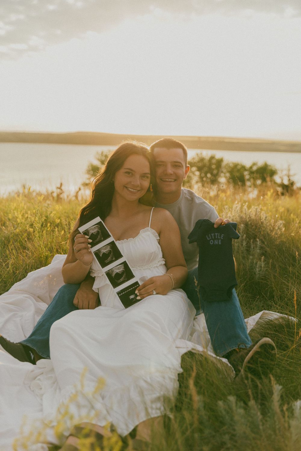 A couple sits together in a grassy field at sunset sharing intimate moments in a series of romantic photos.